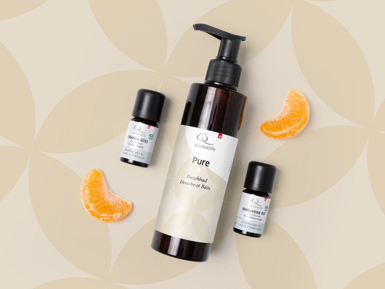 Duschbad-Grundlage und Mandarinenschnitze liegen auf einem gekachelten Boden.