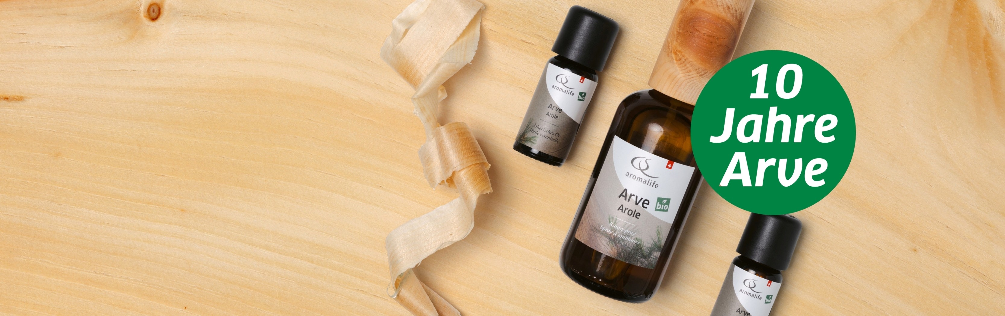 Arve ätherisches Öl und Arve Raumspray liegen auf einem Tisch aus Arvenholz