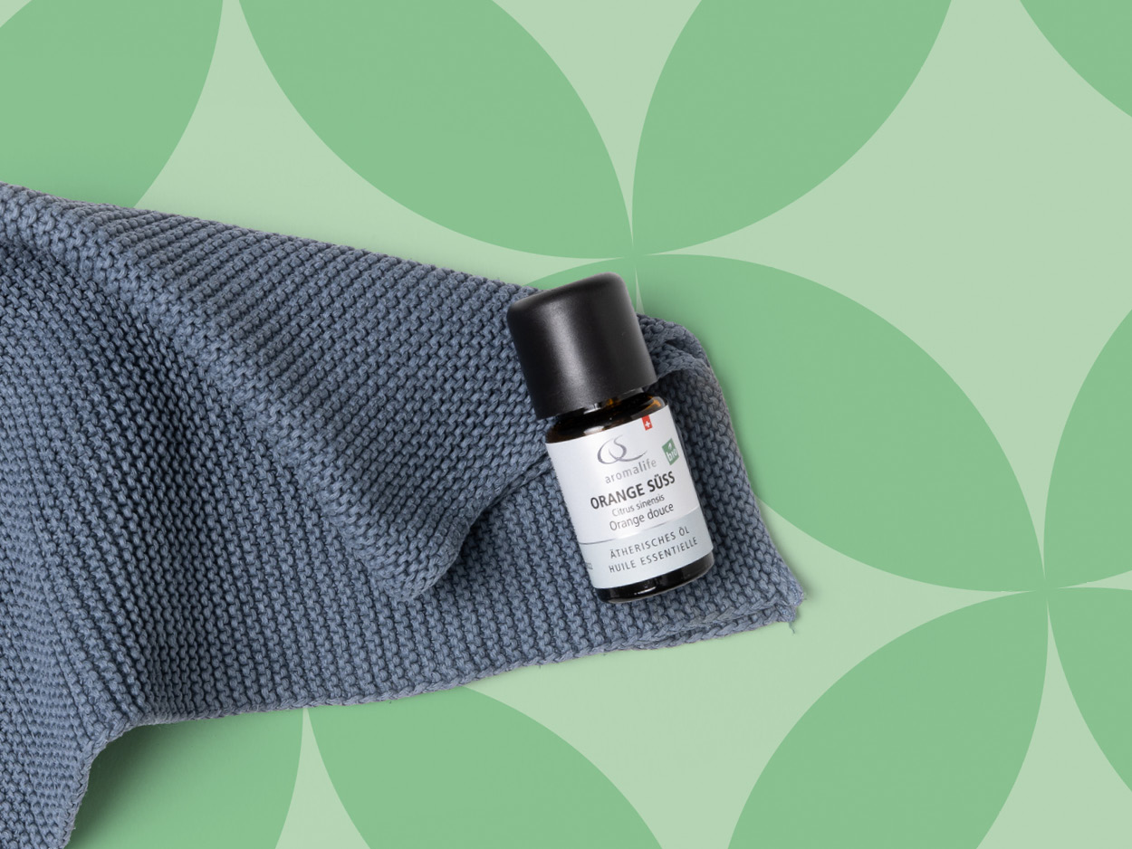 Mikrofaserlappen liegt mit einem Fläschchen ätherischen Öles auf einem gekachelten Boden.